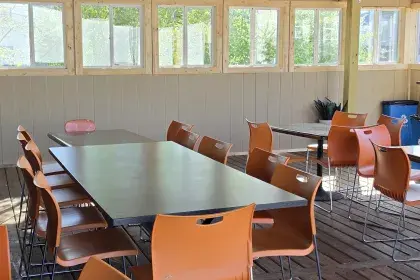 The covered back patio at Dukem Ethiopian Restaurant, with orange chairs and tables on a wood deck.