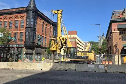 Photo showing construction equipment in street with buildings in background. For information call 651-266-6100.